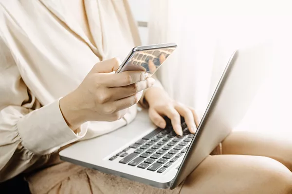 Persoană care solicită un credit online pe 6 luni folosind laptopul și cardul bancar