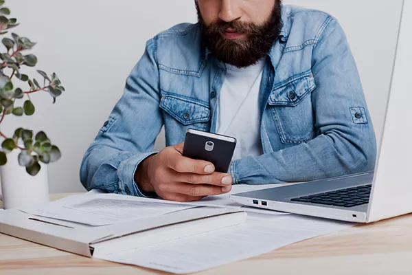 Persoană care verifică telefonul și documentele financiare analizând opțiuni de credit pentru șomeri